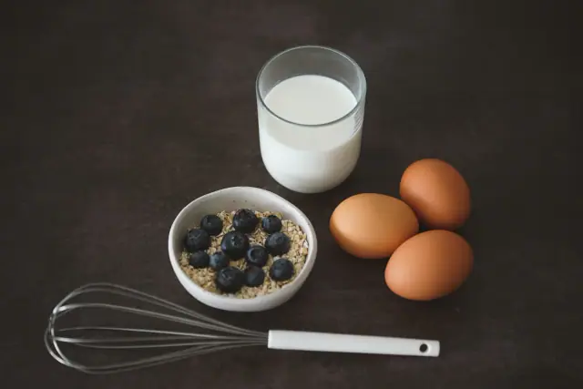 Oatmeal with blueberries beside eggs and milk