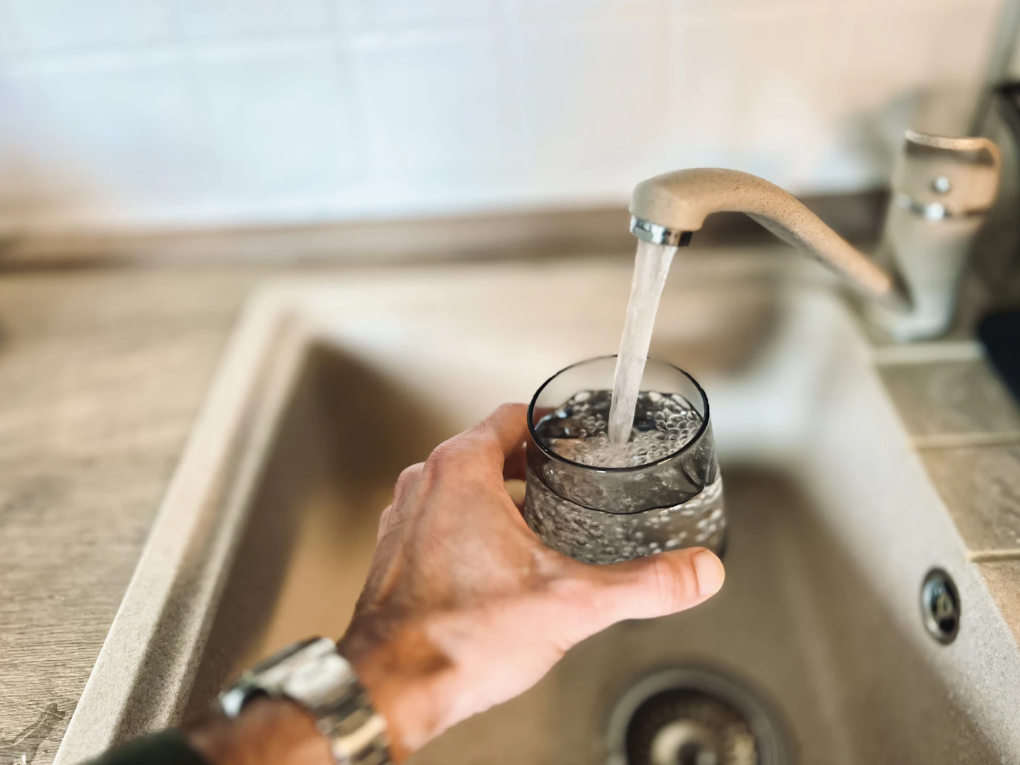 A glass being filled with water from a kitchen tap