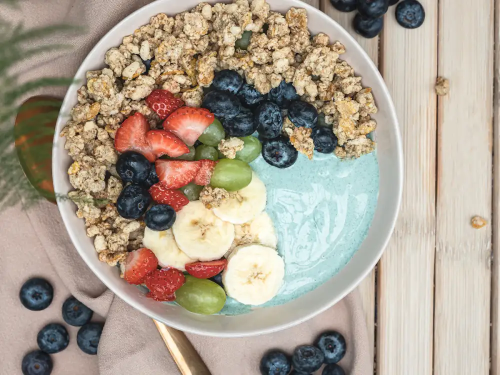 A breakfast bowl topped with granola and mixed fruit